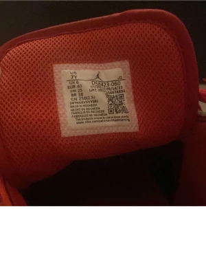 Air Jordan 1 Mid Svart/Röd - Säljer ett par Air Jordan 1 Mid i svart och rött med klassisk Nike swoosh på sidan. Skorna har perforerad tå, röda snören och svart/röd ovandel i läder. Ikonisk Jumpman-logga på plösen och Wings-logga på sidan. Perfekta för dig som gillar streetstyle.