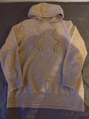Riktig cashmere hoodie - Äkta cashmere, där av blir priset högre!😃Mysig beige stickad hoodie med huva och dragsko med metalländar. Tröjan har ribbade muddar vid ärmslut och nederkant, perfekt för en avslappnad och stilren look. Passar dig som gillar enkel och klassisk stil. Använd 2 gånger endast!
