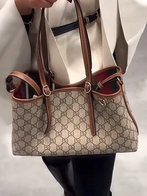 INTRESSEKOLL Gu**i  axelväska med monogram - Snygg axelväska  i klassiskt beige monogramtyg med bruna läderdetaljer och justerbara axelremmar. Väskan har en rymlig öppen design, perfekt för dig som vill ha en trendig och tidlös accessoar. Använd få tal gånger till kommer rem för att bära cross body 