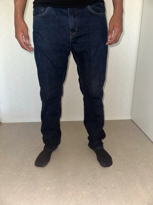Mörkblå raka jeans från lager 157 - Säljer ett par klassiska mörkblå jeans från lager 157 med rak passform och fem fickor. Jeansen har en stilren look med diskreta sömmar och knappgylf. Perfekta för dig som gillar en tidlös och enkel stil.