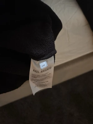 Svart hoodie från Axel Arigato XS - Säljer en svart hoodie från Axel Arigato i storlek XS. Sömmen vid halsen har lossnat litegrann 