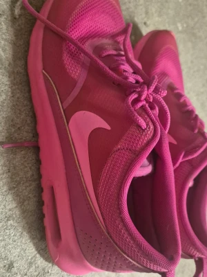 Rosa Nike sneakers - Snygga rosa Nike sneakers med klassisk swoosh-logga på sidan. Skorna har ovandel i mesh för bra ventilation och en bekväm sula. Låga i modellen och med matchande rosa skosnören. Perfekta för dig som vill sticka ut med färg på fötterna. Små i storleken.