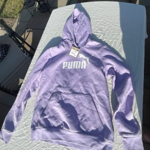Lila PUMA hoodie dam med prislappen kvar - Säljer en lila hoodie från PUMA med prislappen kvar så endast testad. Den är i storlek Medium. Säljes pga att jag har fått den i present och den är för liten🤩☺️