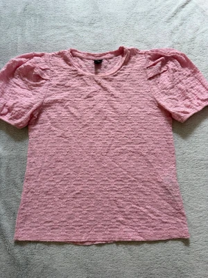 Rosa spetsmönstrad topp från vero moda - Söt rosa topp med korta ärmar och spetsmönster.