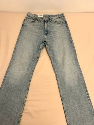 Ljusblå raka jeans med hög midja - Säljer ett par ljusblå jeans med rak passform och hög midja. Jeansen har klassisk femficksdesign och är tillverkade i denim med en snygg tvättad look. Perfekta för en avslappnad och trendig stil.