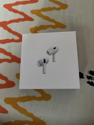 Apple AirPods Pro trådlösa hörlurar - Säljer ett par vita Apple AirPods Pro med laddningsetui. Hörlurarna är trådlösa in-ear-modeller med silikontoppar och levereras i originalförpackning med laddkabel och manual. Snygg och kompakt design i blank plast, perfekt för musik och samtal.