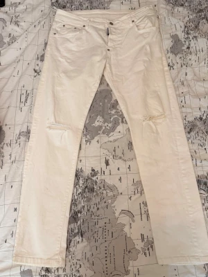 Vita ripped jeans från Dsquared2 - Säljer ett par vita jeans från Dsquared2 med slim fit och slitningar vid knäna. Jeansen har klassisk femficksdesign, knappgylf och är tillverkade i ett mjukt bomullsmaterial. Perfekta för en trendig och avslappnad look.