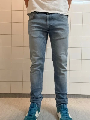 Replay anbass - Säljer ett par ljusblå slim fit jeans från Replay med klassisk femficksmodell och snygga slitningar. Jeansen har en skön stretchig denim och läderpatch med Replay-logga bak i midjan. Perfekta för en avslappnad och trendig look.