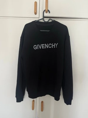 Svart sweatshirt från Givenchy pris kan diskuteras - Snygg svart sweatshirt från Givenchy med vit logotyp på bröstet. Klassisk rund halsringning och långa ärmar. Perfekt för dig som gillar stilrena och exklusiva plagg med streetwear-vibe.