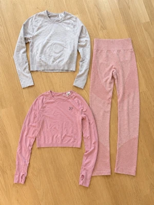 Träningsset med tröjor och tights - Rosa tröja strl M, orangea byxor strl M och beige tröja strl L. Säljer ett träningsset med en beige långärmad crop top, en rosa långärmad crop top med tumhål och matchande orange  tights. Alla plagg är i stretchigt material, perfekta för gym eller yoga.