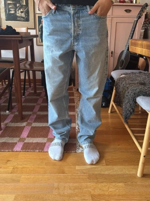 Ljusblå raka jeans - Säljer ett par ljusblå jeans med rak passform och klassisk femficksdesign. Jeansen har hög midja och är tillverkade i ett slitstarkt denimtyg. Perfekta för en avslappnad och trendig look.