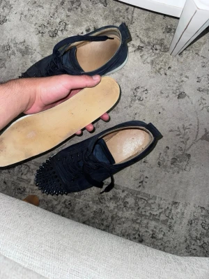 Marinblåa Christian Louboutin sneakers - Säljer ett par marinblåa sneakers från Christian Louboutin i mocka med coola nitar på tån. Skorna har vita sulor och klassisk snörning. Perfekta för dig som vill sticka ut med en edgy och lyxig stil 8/10 i skick.