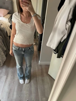 Vit och blå tröja Holly&Whyte - Supersöt topp från Holly & Whyte by Lindex i vitt med små blå mönster. Toppen har korta ärmar, rund halsringning och vågiga kanter. Perfekt för dig som gillar en söt och enkel stil.