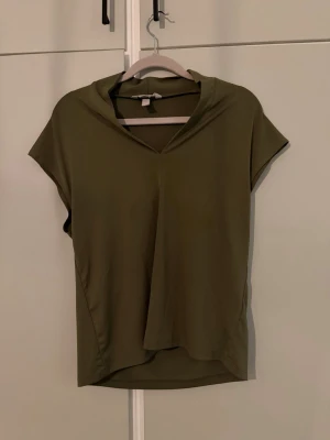 Olivgrön kortärmad topp från H&M - Snygg olivgrön topp från H&M med korta ärmar. Superfin!