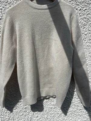 Beige stickad tröja från SAMS - Mysig beige stickad tröja från SAMS i storlek S. Tröjan har rund halsringning och är tillverkad i ett mjukt, strukturerat material. Perfekt för lager-på-lager och enkel att matcha med olika outfits.