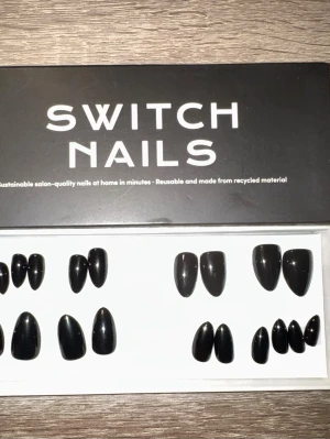 Switch Nails Blackout Almond Short - Snygga press-on naglar från Switch Nails i modellen Blackout. Naglarna har en kort mandelform och är helsvarta. Tillverkade av återvunnet material och kan återanvändas. Perfekt för dig som vill ha en stilren och edgy look. Säljes utan tillbehör.