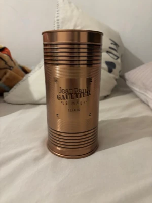Jean Paul Gaultier Le Male Elixir - Jean Paul Gaultier Le Male Elixir parfym i en metallisk kopparfärgad burk med räfflad design. Flaskan rymmer 125 ml och har en modern, maskulin look. Perfekt för dig som gillar exklusiva och ikoniska dofter.knappr använd 100 ml kvar minst
