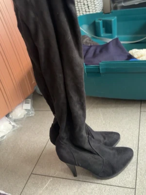 Svarta overknee stövlar med klack - Säljer ett par svarta overknee stövlar med spetsig tå och hög klack. Stövlarna är i mockaimitation och har dragkedja på insidan. Perfekta för att lyfta vilken outfit som helst.