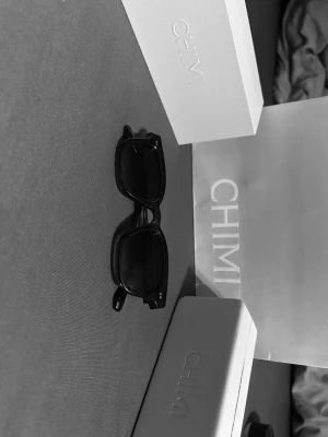 Mörkblå solglasögon från CHIMI - Snygga mörkblå solglasögon från CHIMI med klassisk, rektangulär form och bred båge. Glasögonen har en stilren look och passar perfekt till alla outfits. Levereras med originalfodral och box.