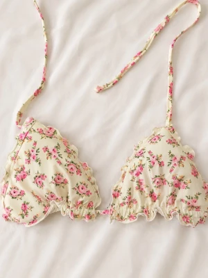 Blommig bikiniöverdel med volang - Supersöt bikiniöverdel med blommigt mönster i rosa och grönt på en ljus botten. Triangelformade kupor med volangkant och smala knytband i nacken och ryggen. Perfekt för sommarens stranddagar!