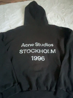Svart hoodie Acne Studios - Svart hoodie från Acne Studios. Tillverkad i mjukt bomullsmaterial och har en avslappnad passform. Perfekt för en chill och trendig look. Dålig kamera kvalitet den är helt ny med pris lapp, hör av er för minsta funderingar!