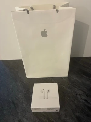 Apple AirPods 2019 gen 2 trådlösa hörlurar - Säljer ett par vita Apple AirPods i originalförpackning. köpta i apple butiken i täby för 1790 kr. Snygg och stilren design med slimmad form, perfekt för dig som vill ha trådlösa hörlurar med bra ljud och enkel anslutning till iPhone eller andra Apple-enheter. Kommer i klassisk Apple-förpackning.