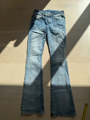 Ljusblå diesel jeans - Säljer ett par ljusblå bootcut diesel jeans med snygga slitningar och klassisk femficksdesign. Jeansen har låg midja och lätt utsvängda ben. 