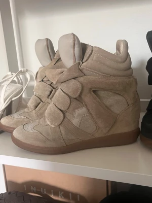 Beige Isabel Marant bekett sneakers - Jättesnygga beiga sneakers från Isabel marant i modellen bekett. Skorna är gjorda i mocka med inbyggd kilklack. Perfekta i vår och sommar!! Kommer i ett väldigt bra skick tillsammans med dustbag🩷😇