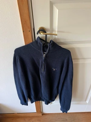 Halfzip tröja Gant - Mörkblå stickad tröja från Gant med halvzip. Tröjan är i fint skick! Storlek M men lite mindre i storlek.