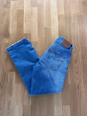 Levi's 501 90’s blå raka jeans - Klassiska blå Levi's 501 90’s jeans med rak passform och mellan midja. Jeansen har fem fickor, knappgylf och den ikoniska läderpatchen bak. Storlek W26 L30