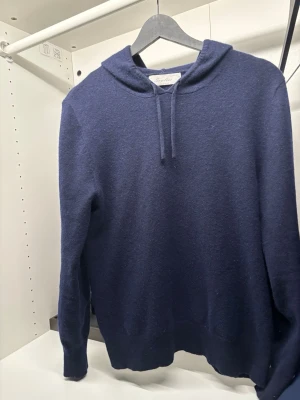 Sayless - Snygg mörkblå kashmir hoodie från Sayless med huva och dragsnören. Tillverkad i mjuk ullblandning som känns riktigt skön mot huden. Klassisk passform med ribbade muddar och enkel design utan tryck eller mönster. Perfekt för dig som gillar stilrena plagg. Toppen skick, M men sitter nästan som S🙌😊