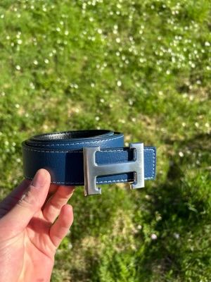 H bälte blå - Tja säljer nu ett helt nytt bälte som är riktigt snyggt om man vill kan man vända på det så kan man ha den svarta, 110cm.                                            Hör av er vid frågor!