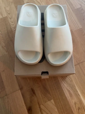 Adidas Yeezy Slides Cream - Adidas yeezy slides i färgen cream. De är i storleken us 9, 43. De är använda ett enstaka gånger men är i väldigt gott skick. Perfekta nu till sommaren. 