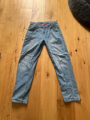 Ljusblå jeans från TRYVLS - Säljer ett par ljusblå jeans från TRYVLS i modellen Arctic Urban Loose Denim. Jeansen är raka i benen och har klassisk femficksdesign. Materialet är 100% bomull vilket gör dem sköna och slitstarka. Perfekt för dig som gillar en avslappnad och trendig look.