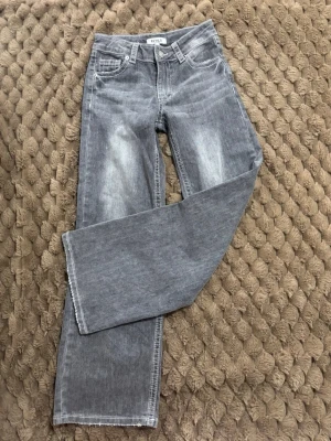 Low waist baggy jeans - Snygga grå jeans från RYVLS, baggy fit  och vit kontrastsöm. Jeansen har klassisk femficksdesign och en lätt tvättad look med slitningar på låren. Perfekta för en avslappnad och trendig stil.
