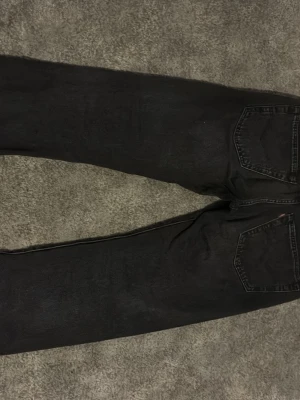 Svarta raka jeans - Säljer ett par svarta jeans med rak passform och klassiska fem fickor. Jeansen har en enkel design utan synliga loggor och är tillverkade i ett robust denimtyg. Perfekta för en avslappnad och stilren look.