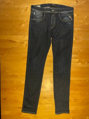 Mörkblå skinny jeans från Replay - Säljer ett par mörkblå skinny jeans från Replay med klassisk femficksdesign och snygga kontrastsömmar. Jeansen har en smal passform och är tillverkade i stretchigt denimtyg för extra komfort. Perfekta till vardagslooken!
