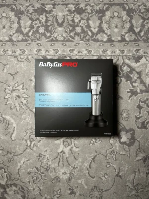 BaBylissPRO CHROMFX hårtrimmer - BaBylissPRO CHROMFX professionell hårtrimmer med digital motor och blad i rostfritt stål. Trimmern är silverfärgad och levereras i originalförpackning med laddningsställ. Perfekt för precision och styling av hår och skägg. Nypris:1809kr 