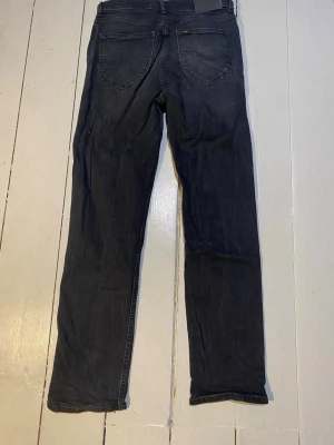 Svarta raka jeans från Lee 14-15Y - Säljer ett par svarta jeans från Lee med rak passform och klassiska bakfickor. Jeansen har en enkel design och är tillverkade i ett mjukt denimtyg som passar perfekt till vardagslooken. Märkeslapp i midjan och snygga sömmar.