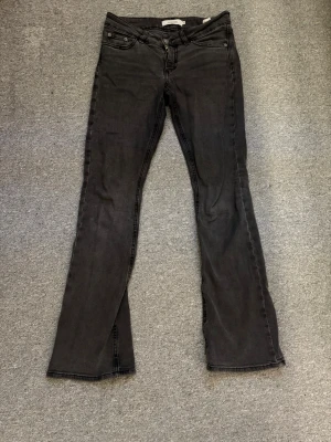 Gråa bootcut jeans från junkyard - Säljer ett par gråa bootcut jeans från junkyard som har coola bakfickor med zigzag-detalj. Jeansen har normal midja och är gjorda i mjuk, skönt denim. Perfekta till vardags💓☺️
