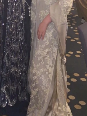 Lång kurdisk klänning - Jag säljer denna kurdiska klänningen som är i färgen beige, du får även med silver smycketsom man har runt omkring klänningen. Har endast användt den 1 gång . Perfekt för dig som vill ha en unik och lyxig look.