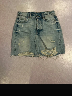 Blå jeanskjol med slitningar - Aldrig använd, har knappar istället för dragkedja till gylf