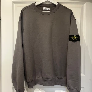 Stone Island - Grey Sweatshirt  - Selling this grey sweatshirt from stone island. Got it from a friend, so have unfortunately no receipt. Wore it a long time ago, and that’s the reason why I’m selling it - it’s too small. In very good condition, besides the label that is damaged. If you have any questions feel free to reach out at any time. 