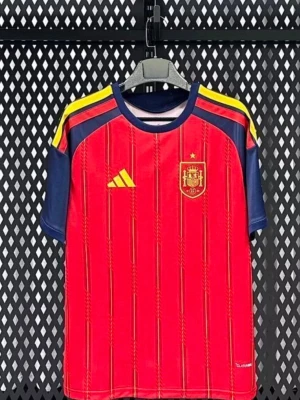 Spaniens röd fotbollströja Adidas - Röd fotbollströja från Adidas med Spaniens landslagsmärke på bröstet. Tröjan har blå ärmar, gula detaljer på axlarna och tunna vertikala ränder. Tillverkad i lätt och ventilerande material, perfekt för träning eller match. Du kan bestämma vilken storlek du vill ha!!! Det kan ta upp till 15-20 dagar för tröjorna att komma!!! 