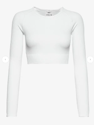 Vit ribbad croppad långärmad topp - Säljer en vit croppad topp från aim'n med lång ärm och ribbad struktur. Toppen har en tight passform och är tillverkad i ett stretchigt material som sitter snyggt på kroppen. Perfekt till jeans eller kjol för en clean look.