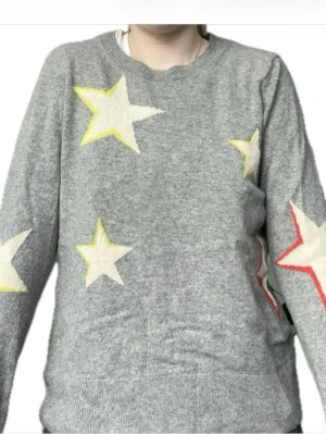 Banana Republic Långärmad Tröja med Färgade Stjärnor – Merino Blend, L (Känns som S) - Snygg och bekväm långärmad tröja från Banana Republic i en mjuk merino blend – perfekt för både vardag och mysiga hemmakvällar. Tröjan har ett lekfullt mönster med färgade stjärnor som sticker ut på en neutral bakgrund och ger en trendig, ungdomlig look.