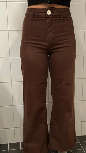 Bruna vida manchesterbyxor - Snygga bruna manchesterbyxor med hög midja och vida ben. Byxorna har rå kant nertill och klassisk femficksdesign. Perfekta för dig som vill ha en retro och chill vibe i garderoben.