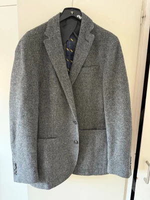 Ralph Lauren kavaj  - Ralph Lauren Stilren grå kavaj i ull med två knappar framtill, breda slag och tre fickor. Kavajen har en klassisk, rak passform och diskreta knappar vid ärmsluten. Perfekt för en dressad look och enkel att matcha med skjorta eller t-shirt. 48 r medium liten large 