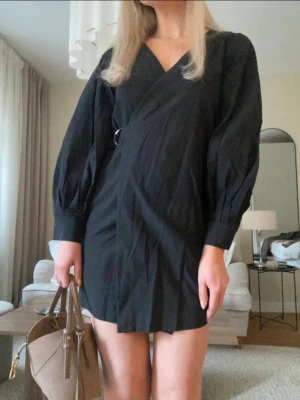 Svart omlottklänning – elegant & tidlös - Superfin svart omlottklänning i en stilren och smickrande modell från & Other Stories.  Klänningen har långa, lätt puffiga ärmar och knyt-/spänndetalj i midjan som ger en fin passform. Perfekt både till vardag med sneakers eller uppklädd med klackar🤍