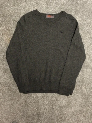Mörkgrå tröja från Morris merinoull - ‼️Står L men passar XS/S‼️.                         Snygg mörkgrå tröja från Morris med diskret broderad logga på bröstet. Tröjan är 100% merinoull och har ribbade muddar vid ärmslut och nederkant. Perfekt för lager-på-lager och stilrena outfits.